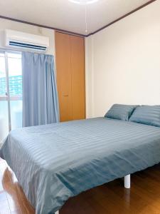 a bedroom with a bed with blue sheets and a window at 折尾Inホテル305 in Kitakyushu