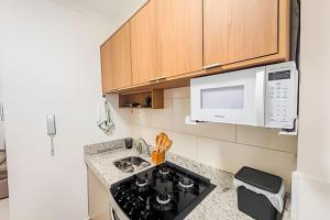 a kitchen with a stove and a microwave at Apartamento com piscina, arcondicionado e vaga in Ourinhos
