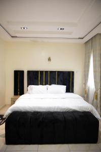 a bedroom with a large white bed with a black headboard at Maa Lagos in Mama