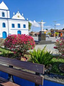 a bench in front of a white building with pink flowers at Apartamento Baixu 1 in Prado