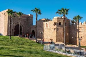 um grande edifício de tijolos com palmeiras em frente em Stay in Rabat with local em Rabat