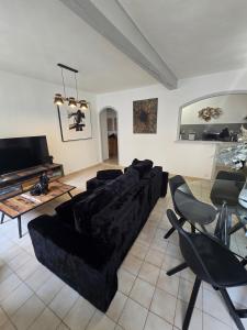 a living room with a black couch and a table at L'écrin des Halles 81 m2 Alès center 8 Beds in Alès