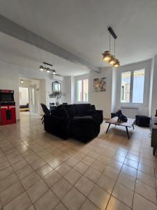 a living room with a black couch and a table at L'écrin des Halles 81 m2 Alès center 8 Beds in Alès