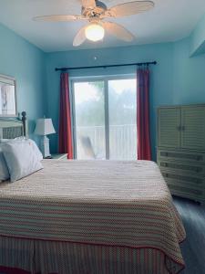 a bedroom with a bed with a ceiling fan and a window at Winter Sale on Now-Sunset Vistas 303N 100s 5 stars in St Pete Beach