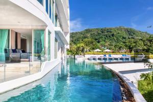 a house with a swimming pool next to a building at Veloche Peaceful Condo In Karon Beach in Ban Karon