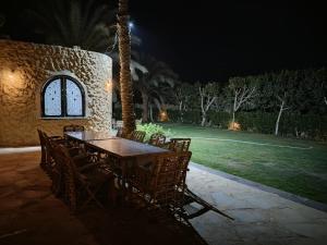 a wooden table and chairs in a yard at night at Slow Tunis in Fayoum Center +8 photos