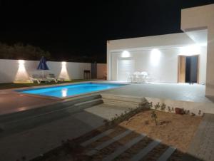 a swimming pool in a backyard at night at Maison TAKWA in Midoun