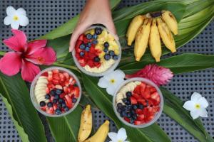 a table topped with bowls of fruit and flowers at Blue Bungalow Moorea in Papetoai