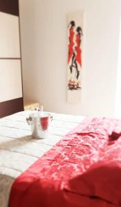 a bed with a red blanket and a cup on it at Residenza IV Novembre in Settimo Torinese