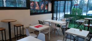 a restaurant with white tables and chairs and windows at White Night in Skopje