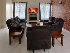a living room with leather furniture and a fireplace at Cottage Ragati in Nanyuki