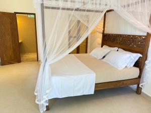 a bedroom with a canopy bed with white curtains at Lily Mirissa in Mirissa +14 photos