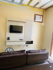 a living room with a couch and a flat screen tv at Casa com piscina in Marechal Deodoro