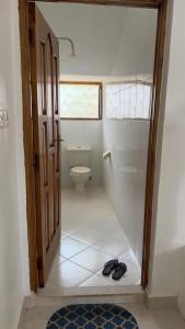 a bathroom with a toilet and a pair of shoes at Casuarina Villa in Malindi