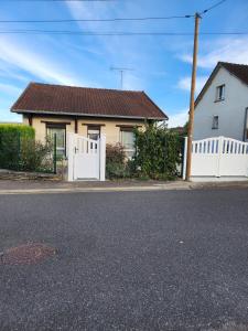 a white house with a white fence and a house at Chez David et Julie in La Bouverie