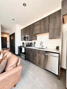 a kitchen with wooden cabinets and a couch in a room at Deer District Studio Apt - One Block from Fiserv and Baird in Milwaukee