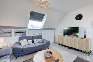Una sala de estar con un sofá y un televisor. en Le Mirabeau - Gare à 100m - Wifi - Bureau - 2 V, en Saint-Pierre-des-Corps