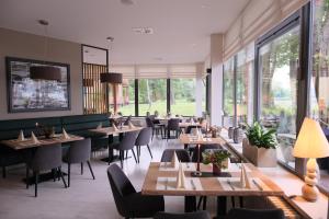 a restaurant with tables and chairs and large windows at Badehaus Hotel & Restaurant in Neubrandenburg