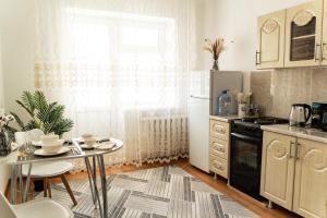 a kitchen with a table and a refrigerator and a window at Уютная квартира в центре города in Taldykolʼ +13 photos