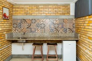 a kitchen with a counter with a sink and stools at Economy Flat in Natal