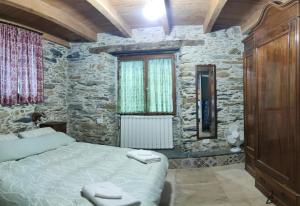 a bedroom with a bed and a stone wall at Villa Art Razzamir in Ponte di Nava