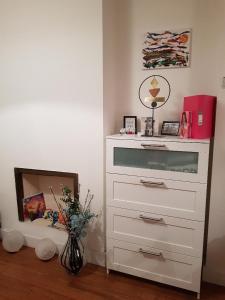 a white dresser with a mirror and a vase with flowers at Small bedroom for 3 people in London