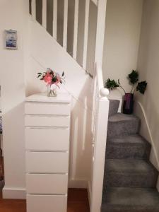 a white staircase with a vase of flowers on a dresser at Small bedroom for 3 people in London