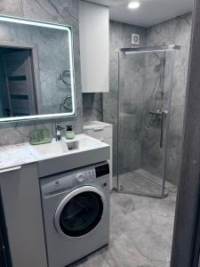 een badkamer met een wasmachine en een douche bij Feliz Stay in Šiauliai