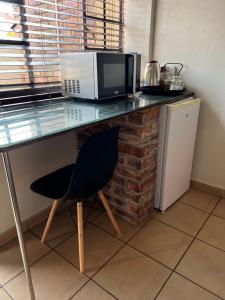 a kitchen with a counter with a microwave and a chair at ForgetMeNot Guesthouse Lydenburg in Lydenburg