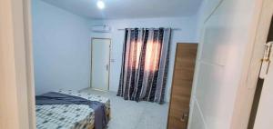 a small bedroom with a bed and a window at Maison piscine privée in Bū Shammah