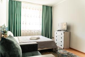 a bedroom with a bed and a window with green curtains at Уютная квартира в центре города in Taldykolʼ
