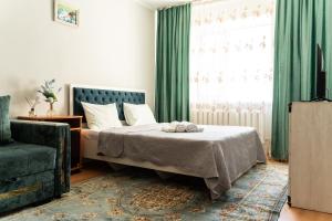 a bedroom with a bed with green curtains and a window at Уютная квартира в центре города in Taldykolʼ