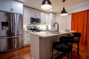 Una cocina con gabinetes blancos y un refrigerador de acero inoxidable. en Historic Kirkwood Location with Arcade & Game room, en Atlanta