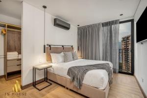ein Schlafzimmer mit einem Bett und einem großen Fenster in der Unterkunft Morph 1302 - Spacious & private apt w BBQ/Jacuzzi in El Poblado + 40 Fotos