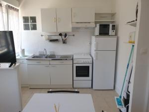 a kitchen with white cabinets and a white refrigerator at L'escapade 12 personnes 6 chambres in Carolles +9 photos