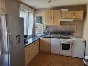 a kitchen with white appliances and wooden cabinets at L'escapade 12 personnes 6 chambres in Carolles