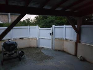a white fence in a yard with a grill at L'escapade 12 personnes 6 chambres in Carolles
