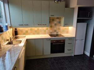cocina con armarios blancos, fregadero y nevera en Parkdale-2 Bedroom House in Sheldon Birmingham, en Birmingham