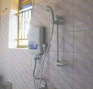 a shower in a bathroom with a hair dryer on a wall at WESTFIELD GARDENS and ACCOMODATION in Namulanda