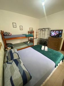a bedroom with two bunk beds and a flat screen tv at Cantinho da amizade in Florianópolis