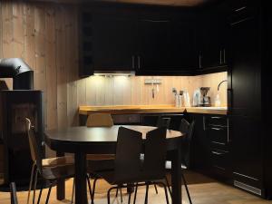 eine Küche mit schwarzen Schränken sowie einem Tisch und Stühlen in der Unterkunft Alpine Crown Trysil in Trysil + 9 Fotos