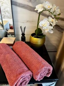 a table with three pink towels and a vase with flowers at Violet Suite in Nyíregyháza