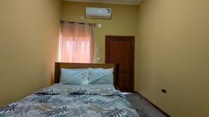 a bedroom with a bed with blue sheets and a window at labert guest house in São Tomé