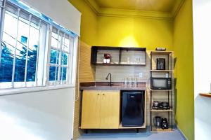 a kitchen with yellow walls and a sink and a window at APTO charmoso com Suíte, Cozinha completa, Wifi, Smart TV, Ar condicionado in Macaé