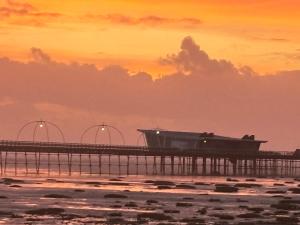 a pier with a boat on the water at sunset at Garrick's Suite-Home away from Home- suitable for couples retreat, Contractors and NHS- free parking in Southport
