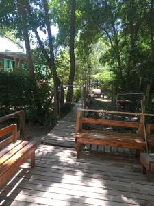 two wooden benches sitting on a wooden walkway with trees at La Morenita del Delta in Estación Delta