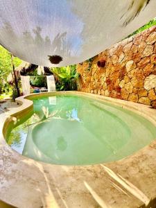 a large swimming pool with a stone wall at La Casa del Árbol in Valladolid