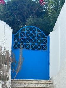 a blue gate on a white fence with trees at évasion bleu in Dar Salah Bey +3 photos