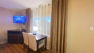 a room with a desk and a table and a television at Royal Inn and Suites in Hemet