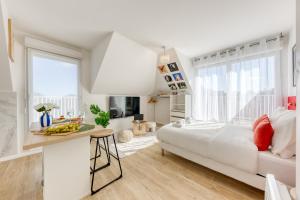 a white bedroom with a bed and a table at Suite Bauhaus - Proche Paris - Terrasse - Netflix in Bobigny